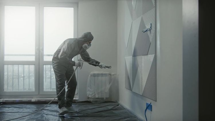 Специалист в защитном костюме опрыскивает газон у частного дома от клещей и комаров